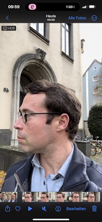 a man in glasses is standing in front of a building